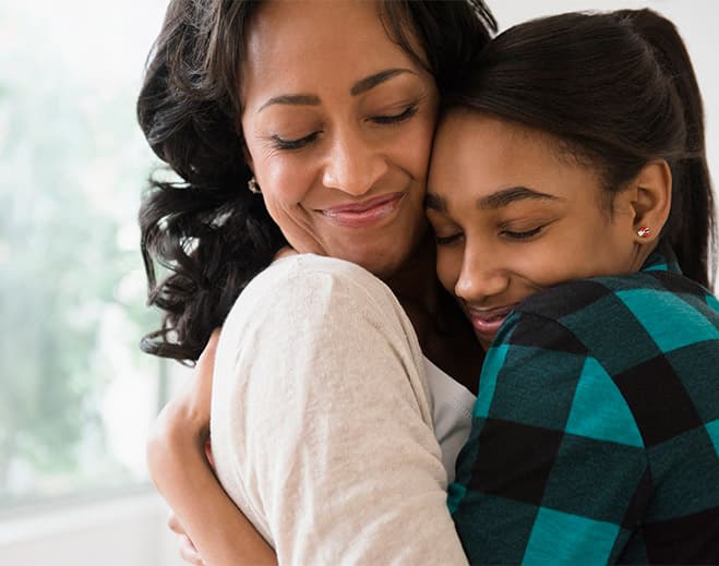 Adult hugging younger person indoors