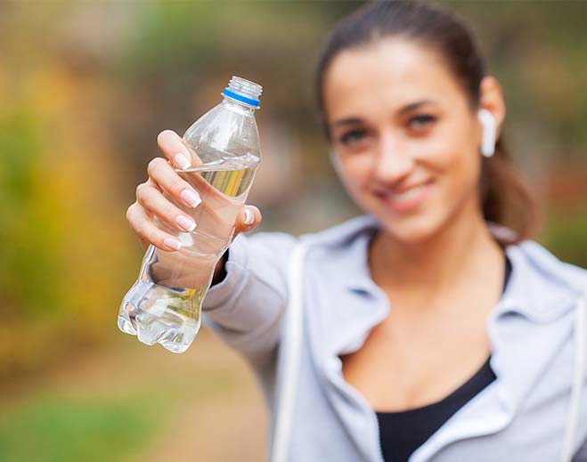 Person holding water bottle toward camera